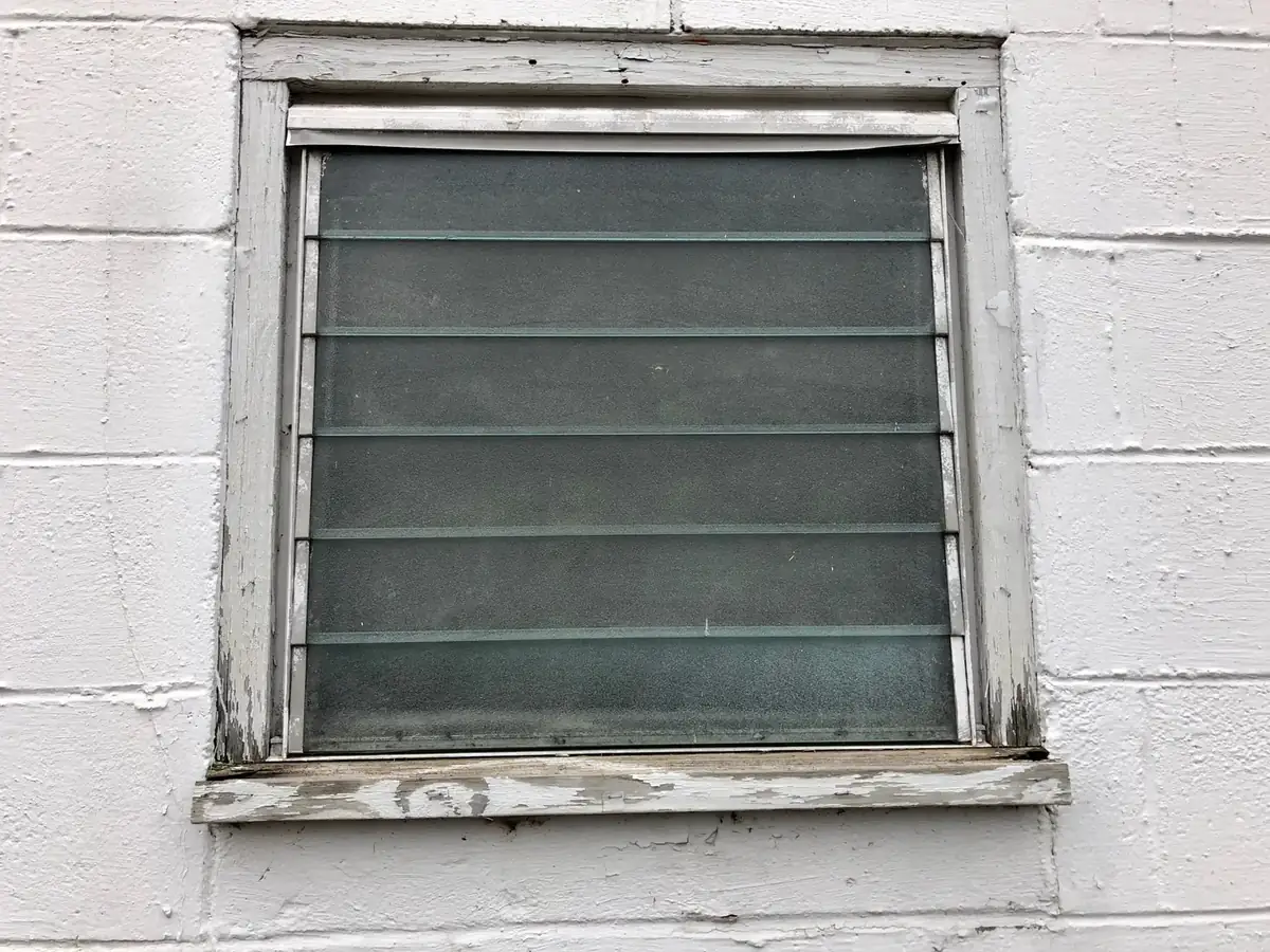 a jalousie window with horizontal glass louvers set in a block wall
