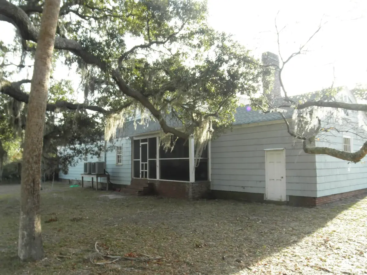 a blue house with a screened side porch under a large oak